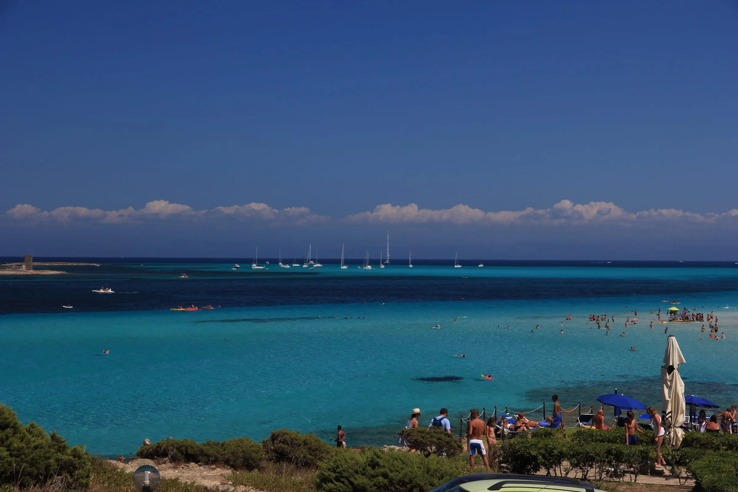 Der Strand La Pelosa bei Stintino im Nordwesten Sardiniens mit türkisem Flachwasser und dem Wehrturm auf der Insel davor