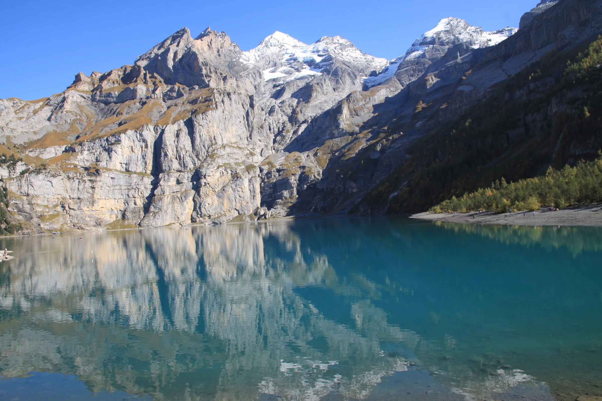 Türkisfarbener Oeschinensee vor steilen Felswänden im Berner Oberland